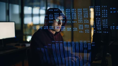 Hooded Young Adult Typing Code at Night