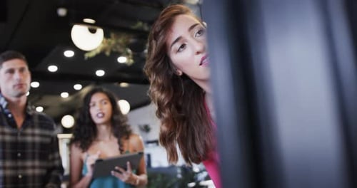 Diversos colegas criativos em discussão, fazendo anotações na parede de vidro no escritório, câmera lenta