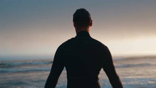 Young Man Stretching Before Surfing at Beach