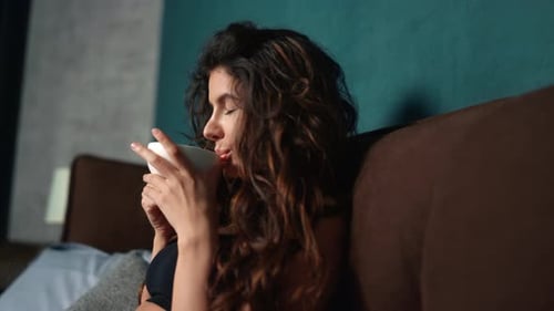 Portrait of Young Woman Enjoying Hot Drink in Bed at Morning. Pretty