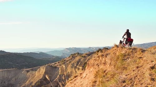 Cyclist Pauses Atop Rugged Mountain Ridge