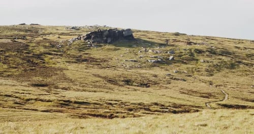 Timelapse of sheep roaming near a jagged rock formation on rugged moorland, Peak District, England.