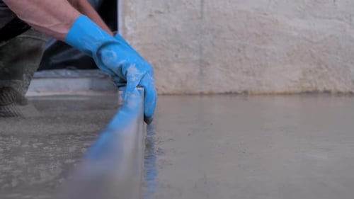 Worker Smoothing Wet Concrete with a Leveler