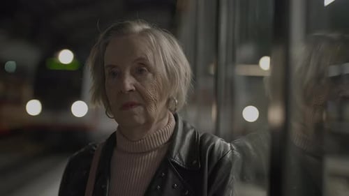 Senior Woman Waiting at Train Station at Night
