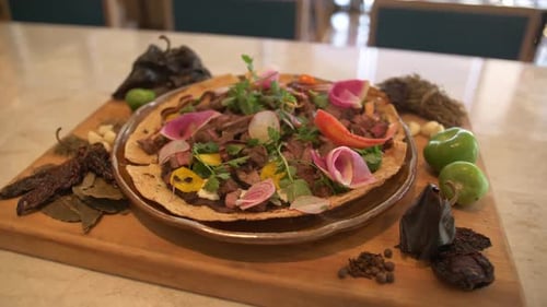 A beautifully presented steak dish being garnished in a modern restaurant kitchen