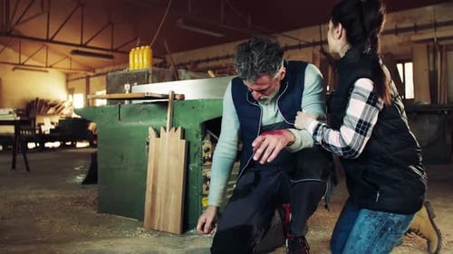 Man And Woman Workers After An Accident In The Carpentry Workshop.