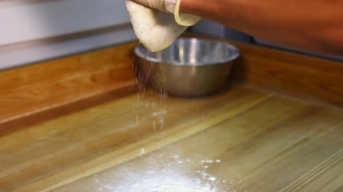 Forming dough for pizza. Hands in gloves of a cook preparing dough in the kitchen. Close-up.