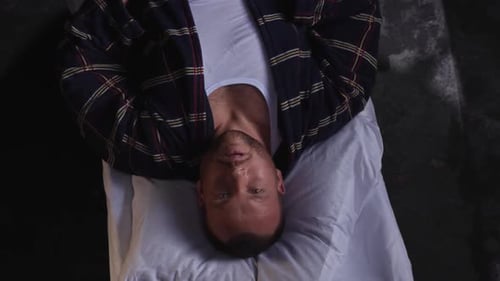 Homme allongé sur un matelas sur le sol regardant vers le haut