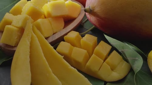 Ripe mango fruits with slices and mango leaves slowly move in the frame.