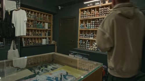 Jeune artiste avec un croquis de graffiti choisissant des peintures au magasin