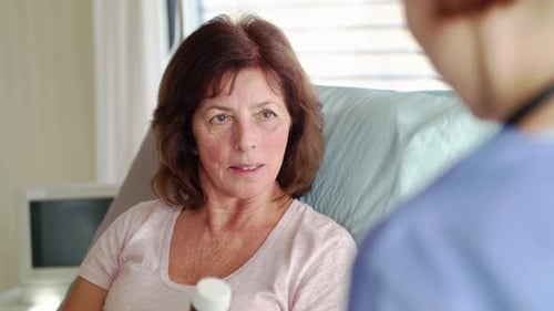 Female doctor explaining medication to senior patient lying in hospital bed