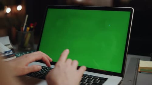 Hands Typing on Laptop with Green Screen at Night