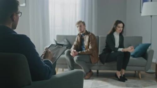 Young Couple on a Counseling Session with Psychotherapist. Back View of Therapist Taking Notes: You