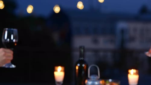 Young Couple Sitting at a Table on the Terrace and Clinking Glasses with Wine on a Date Romantic