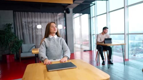 Young Woman Stretching at Desk in Modern Office
