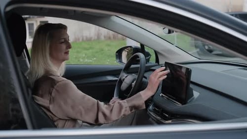 Woman Using Infotainment System Inside Electric Car