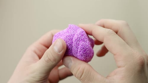 Squishy purple floam being squeezed in hands, showcasing texture and playful motion