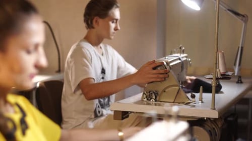 Dressmaker Working on a Sewing Machine in Tailor Studio at Table Professional Occupation of