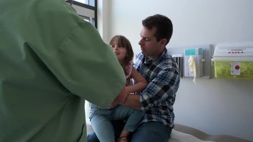 Pediatrician Examining Girl on Fathers Lap in Clinic Examination Room 3539 Years
