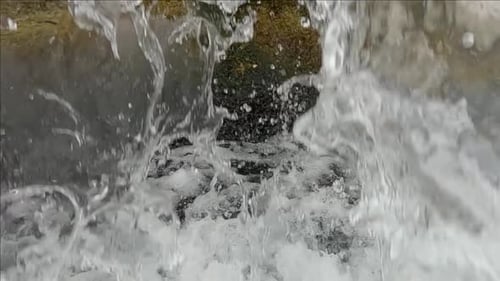 Close up of waterfall in slow motion, camera slowly follows flow of water