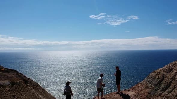 drone video of three men throwing rocks off a cliff into the ocean ...