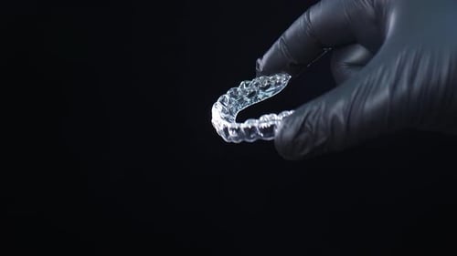 Doctor Orthodontist Holding Transparent Invisalign Aligner on Black Background Plastic Removable