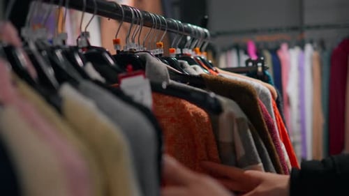 The girl examines each clothes hanger carefully, paying close attention to the fabric and the cut