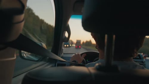 Jovem dirige o carro em trânsito intenso na estrada cheia de caminhões