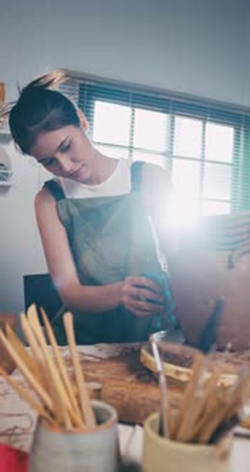 A female ceramicist is creating a new pottery in the workshop.