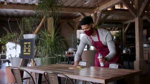 Restaurant Waiter Disinfecting Table During Covid