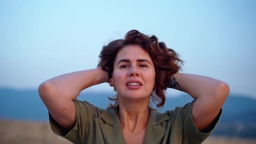 Mujer relajada respirando aire fresco levantando los brazos sobre el cielo al atardecer en verano en las montañas soñando