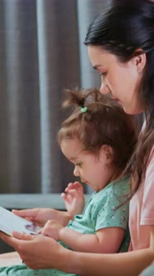 Woman and Child Read Book Together Indoors
