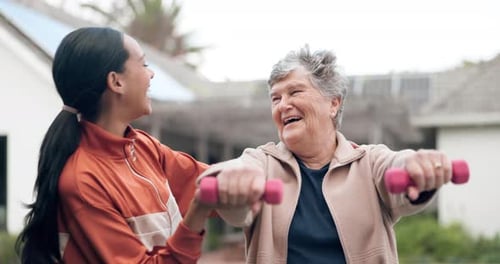Senior Woman Lifts Weights with Young Adult Assistant