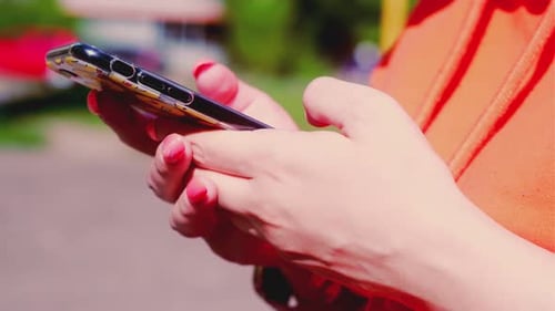 Closeup of a Woman's Hand Holding a Mobile Phone in the Park