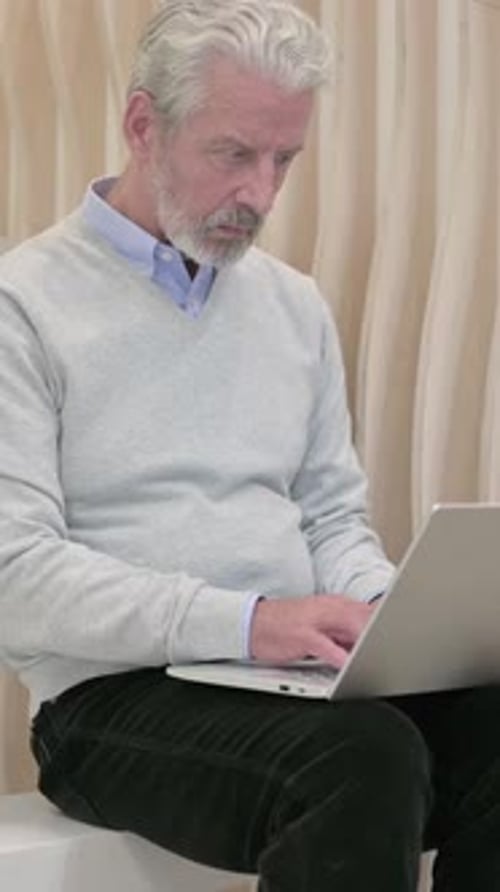 Senior Man Typing on Laptop Indoors