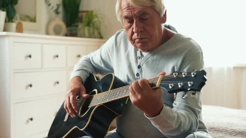 Senior Man Plays Guitar at Home