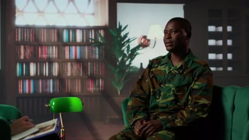 Man in Camouflage Clothing Sits on Green Couch