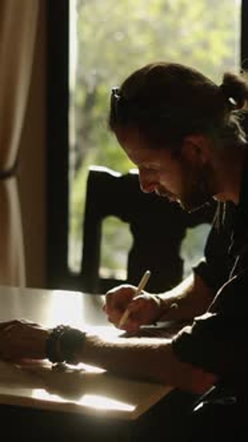Adult Writes at Table by Window