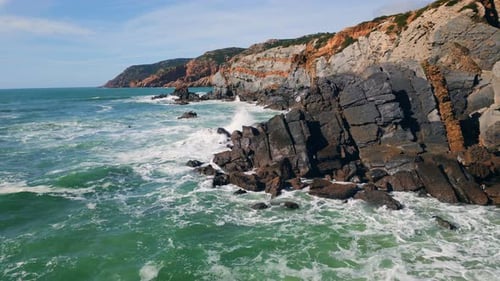 Stürmische Felsenküste mit schäumenden Wellen, brechenden Klippen, Drohne, mächtigem Wasser