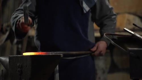 Blacksmith Shaping Hot Metal Rod on Anvil