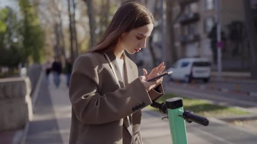 Young Woman Uses Phone on City Street