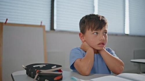 Nachdenkliche Jungensitzstunde Denken im Klassenzimmer, Nahaufnahme, kleines Kind, das lernt