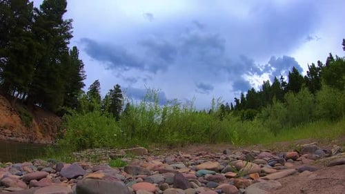 Time lapse of thunder clouds rolling in over a river.