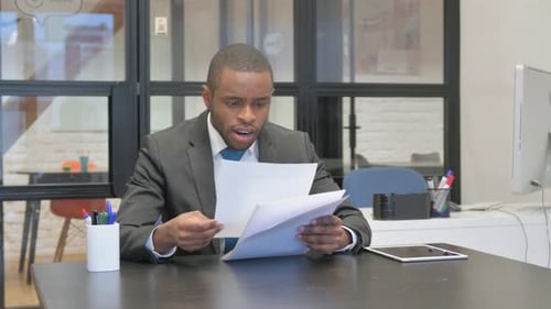 Man Celebrates Reading Documents in the Office