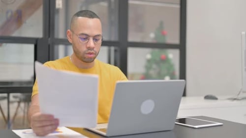 Young Adult Works at Desk with Christmas Tree