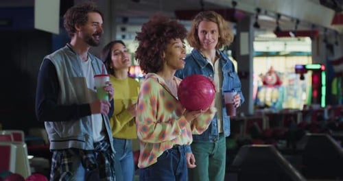 Filmaufnahme einer glücklichen jungen afrikanischen Bowlerin, die einen Strike-Ball wirft und dabei den Sieg jubelt