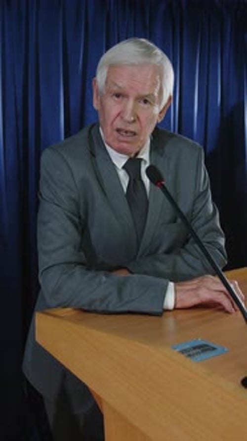 Suited Man Gives Presentation at Podium