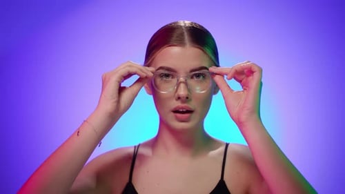 Caucasian Young blonde woman puts on her glass glasses observing and smiling at the camera happily,