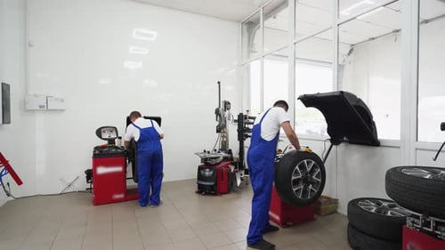 Automechaniker in Uniform arbeiten in einer Reifenwerkstatt mit Ausrüstung Professionelle Wartung von Autorädern