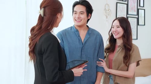 Happy asian couple receiving house key from real estate agent after success property purchase home.
